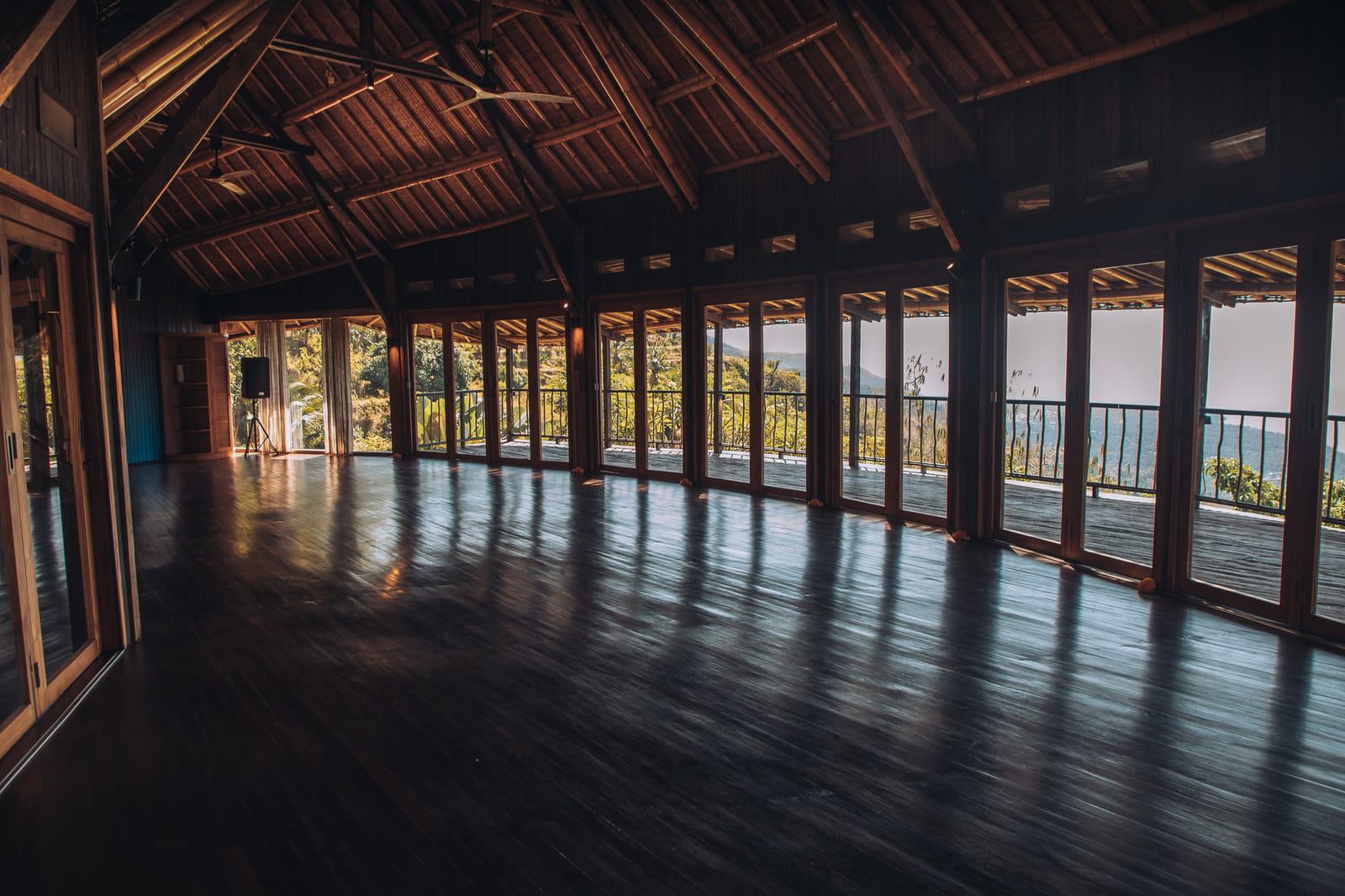 Open-air yoga shala with bamboo roof trusses and floor-to-ceiling windows overlooking the ocean