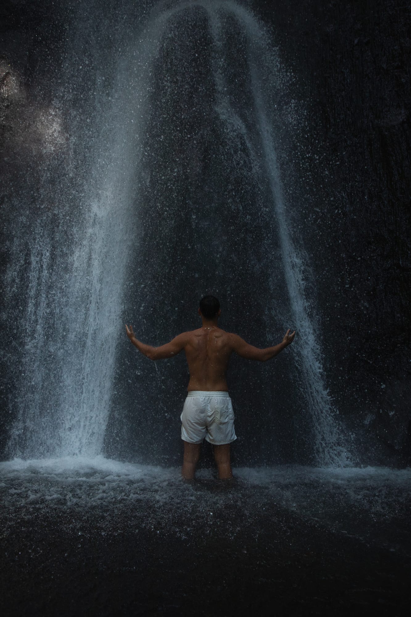 Water fall - man stand at the base of the waterfall in prayer 